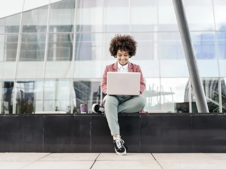 Woman working on a laptop while sitting on steps