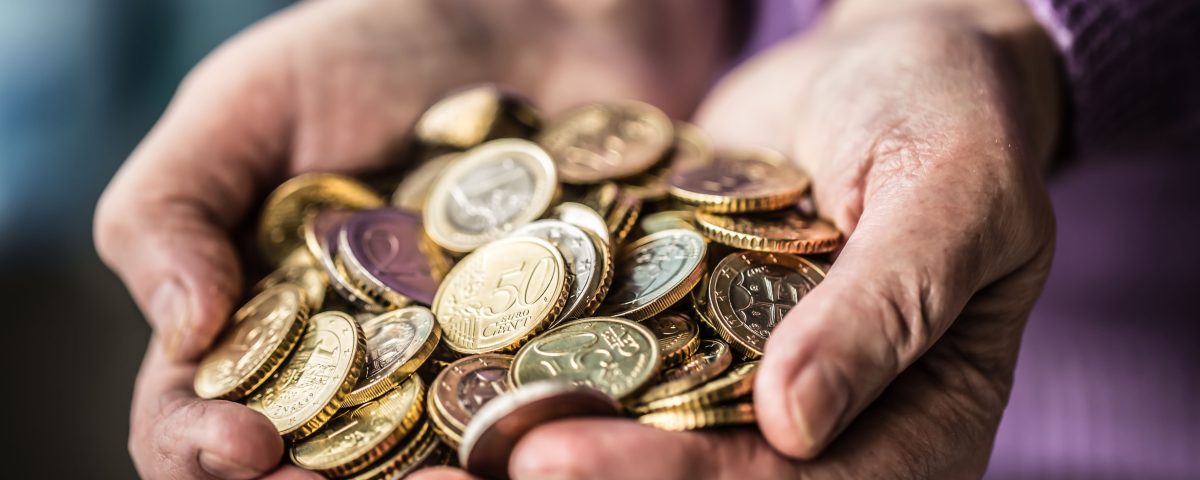 Wrinkled hands holding coins