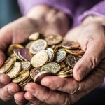 Wrinkled hands holding coins