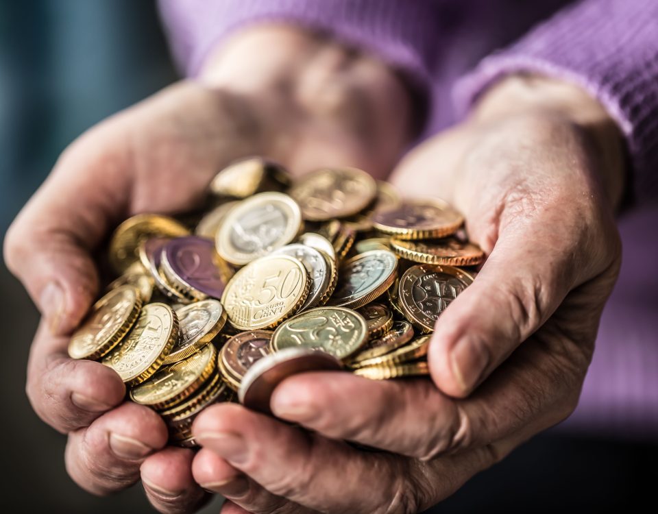 Wrinkled hands holding coins