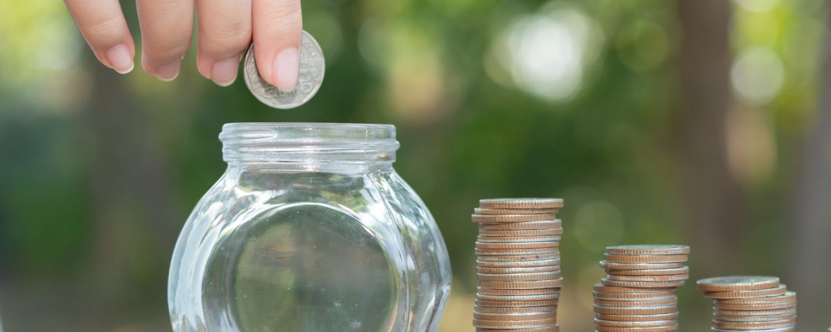Hand putting money coin stack growing business.
