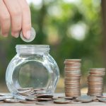 Hand putting money coin stack growing business.